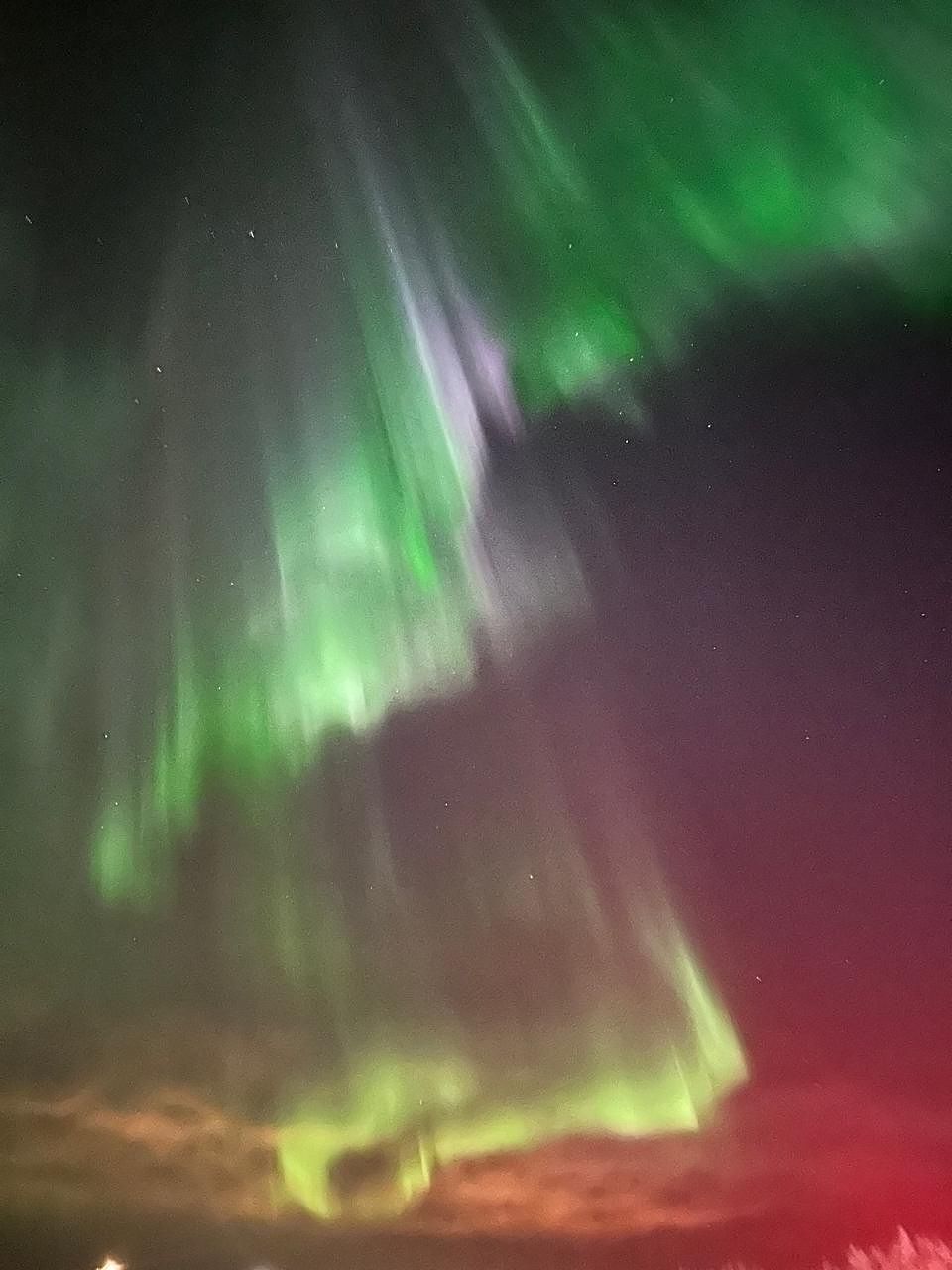 Green and crimson aurora folding across the night sky