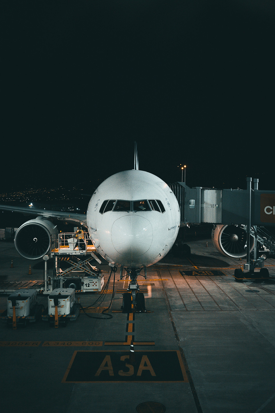 A passenger jet parked nose-in at an airport gate at night